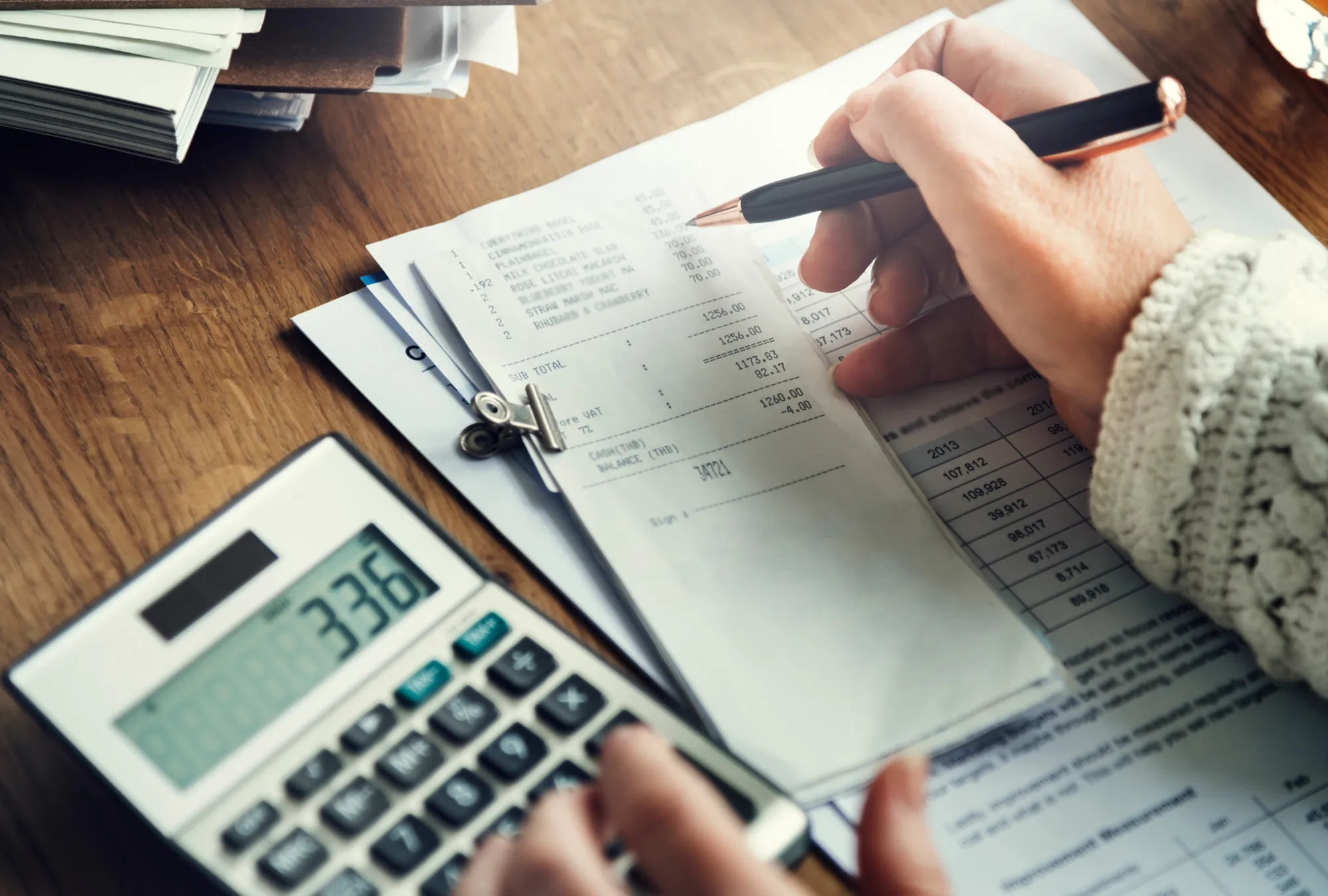 Persona anotando y revisando sus recibos con una calculadora